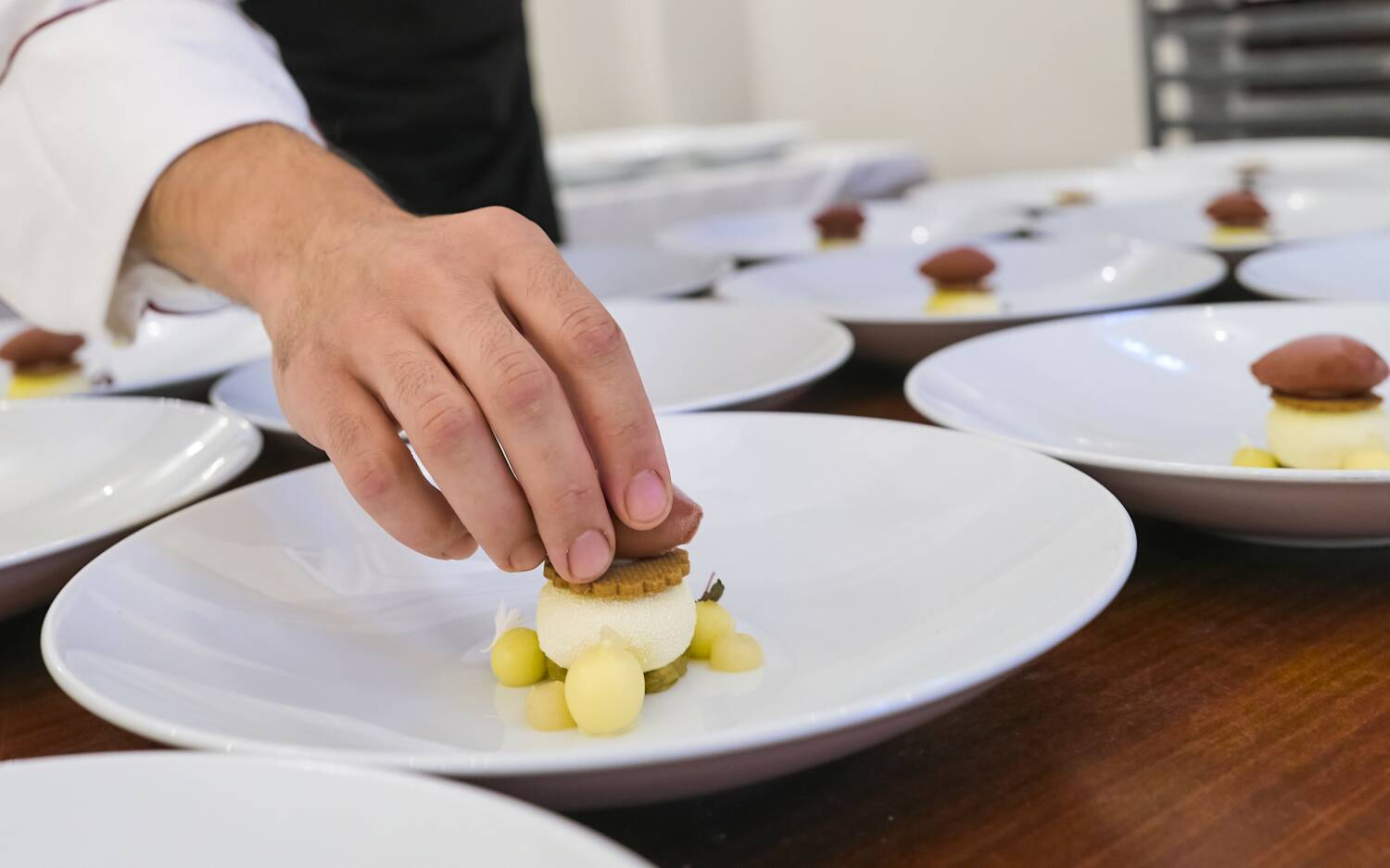 Taro Bünemann konzentriert beim Anrichten der Dessert-Teller / © Marcus Brodt