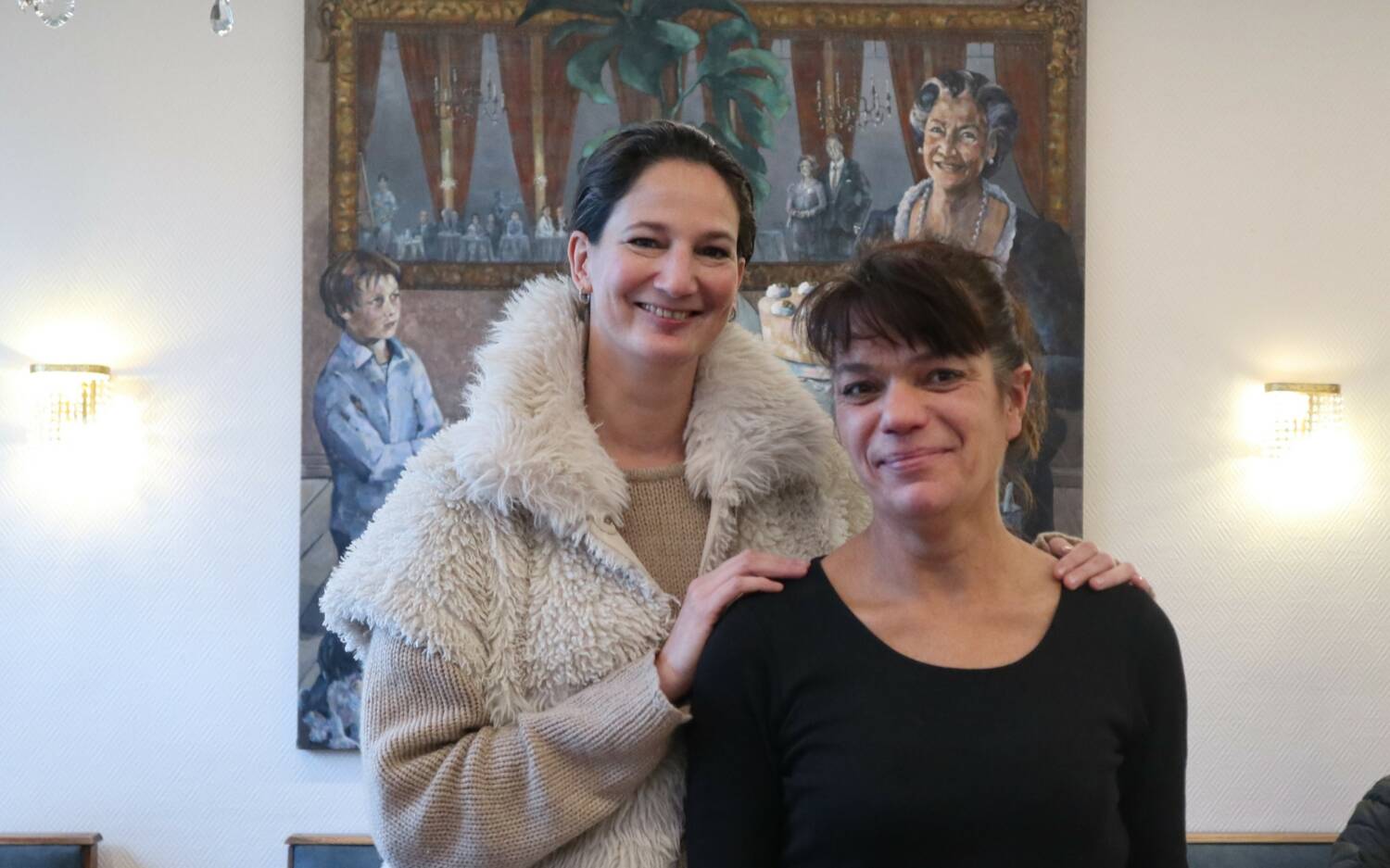 Alexa Grau (l.), Tochter von Inhaberin Angelika Besch, mit der langjährigen Mitarbeiterin Vera vor dem Familienporträt (r.). /©Alina Fedorova 